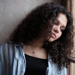 A sad woman leaning on a window.